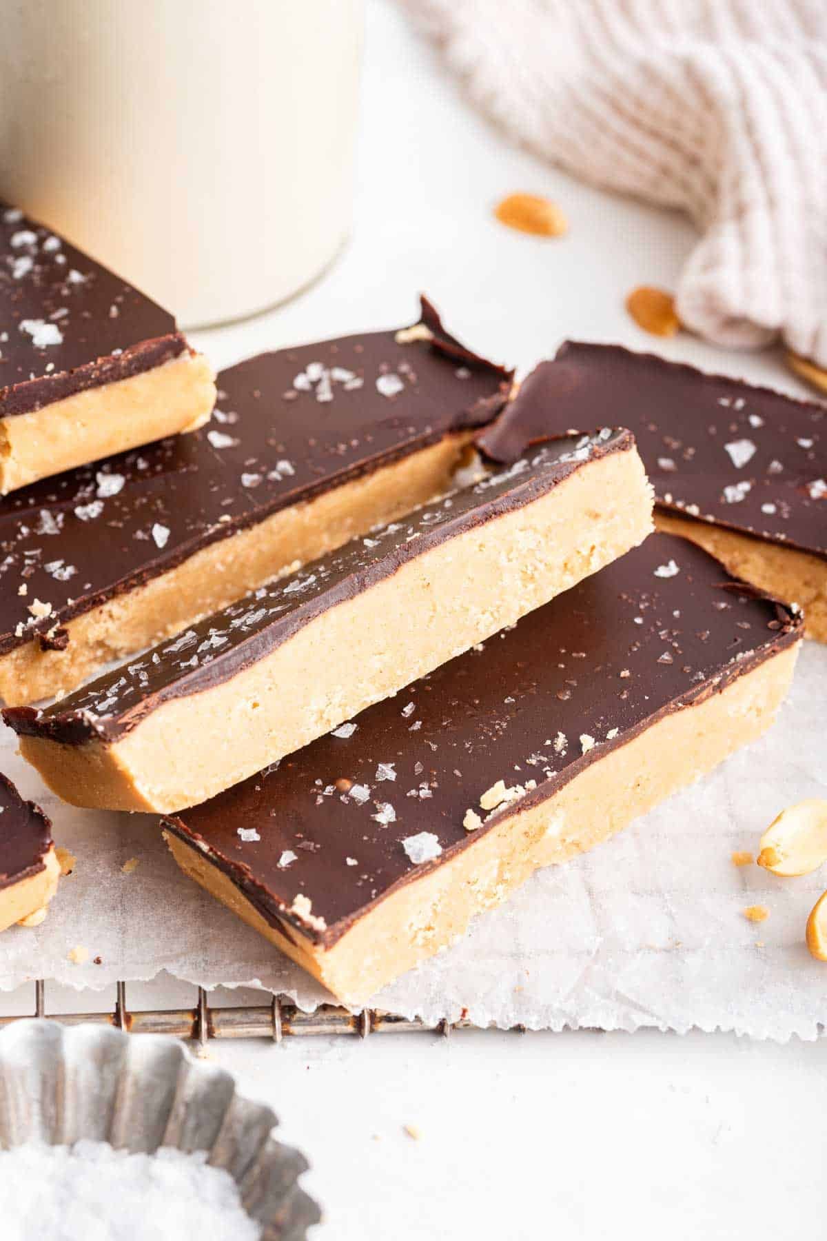 Sliced peanut butter bars on white parchment paper covered in chocolate.