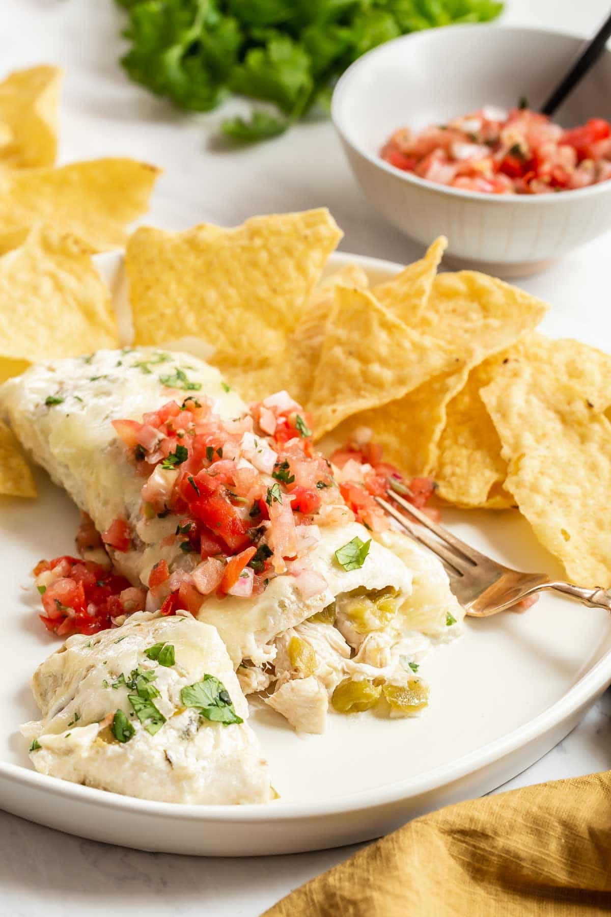 Creamy chicken enchiladas on plate with chips.