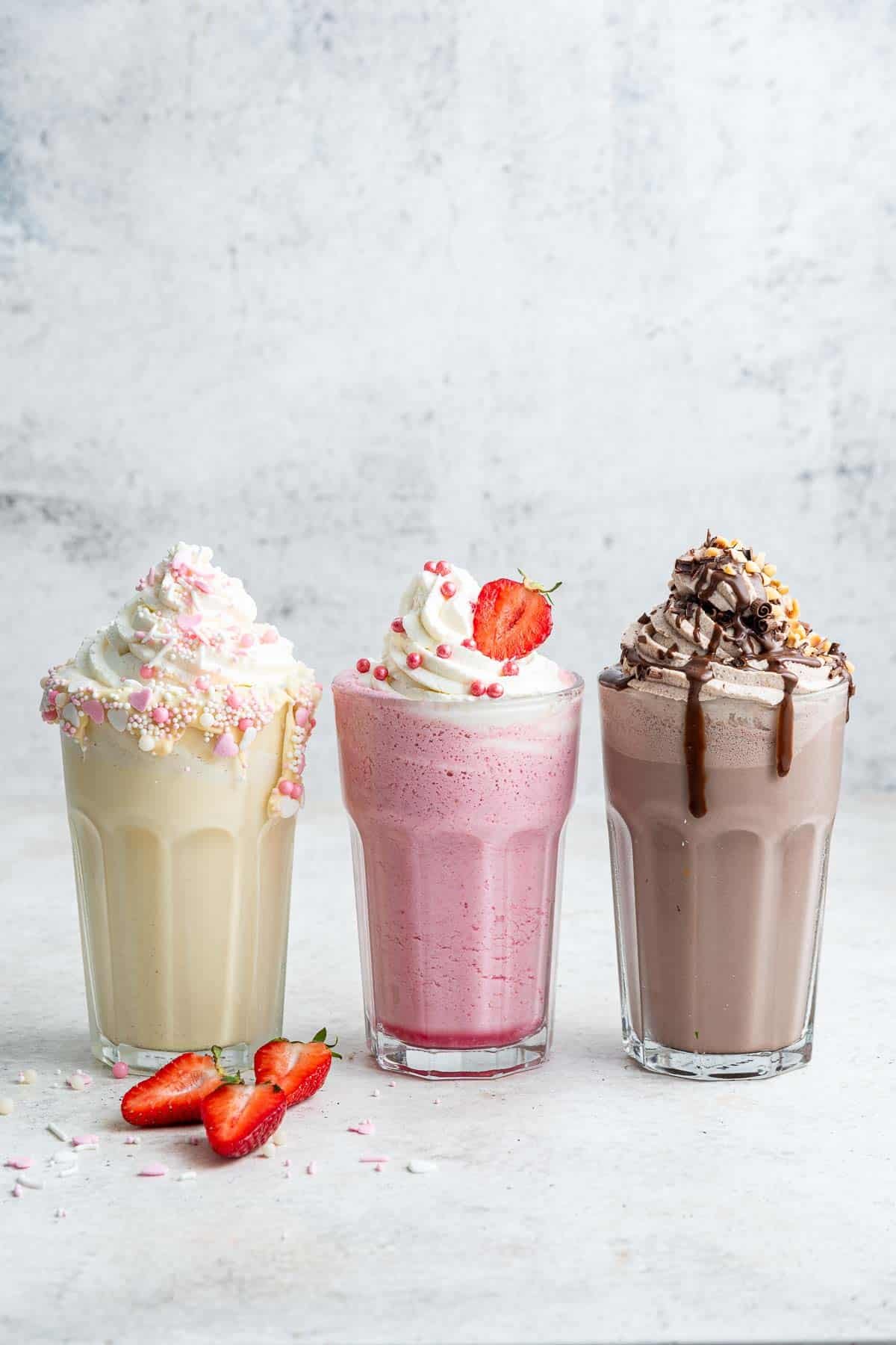 Vertikales Bild von 3 Milchshakes: Vanille, Erdbeere und Schokolade.