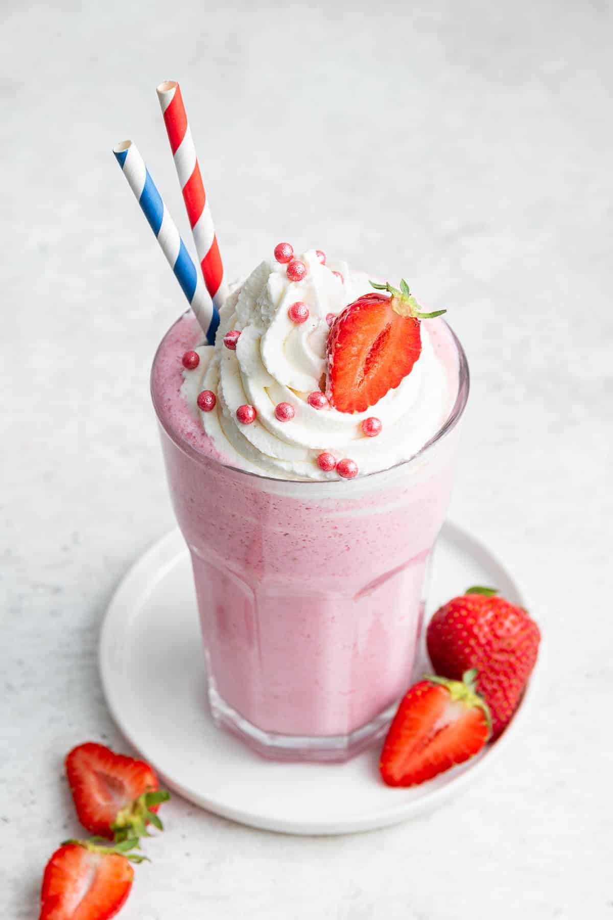 Bestes Milchshake-Rezept für Erdbeeren im Glas, garniert mit 2 Strohhalmen.