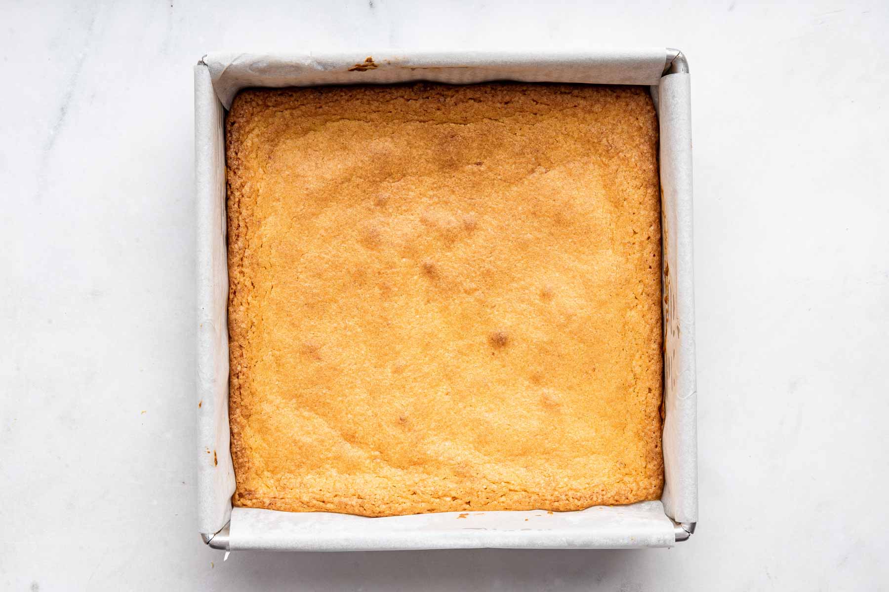 Square baking pan with yellow dessert freshly cooked.